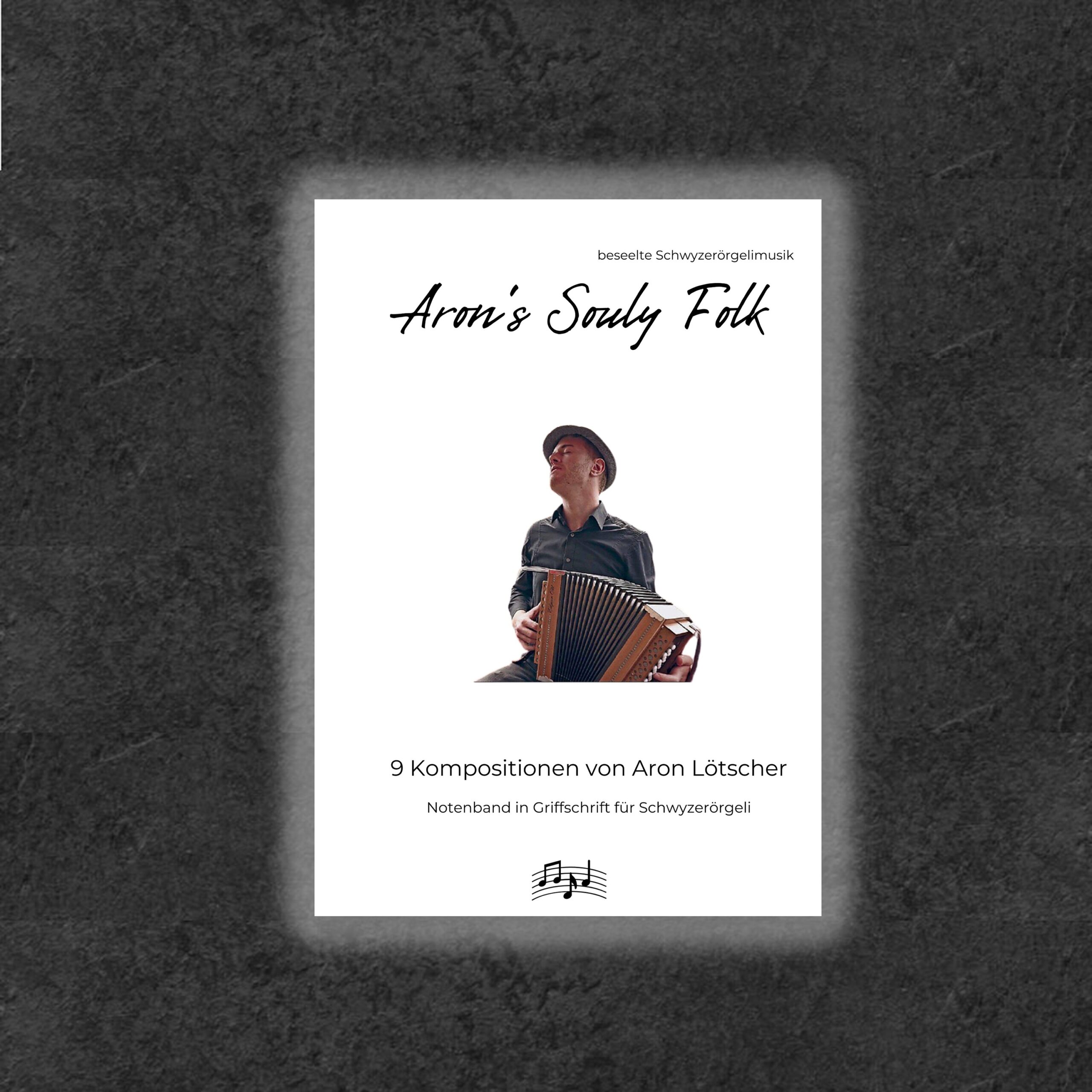 Aron Lötscher spielt ein Schwyzerörgeli. Das Cover seines ersten Notenbands mit dem Titel "Aron's Souly Folk" zeigt ihn in einem dunklen Hemd und Hut, während er nach oben schaut. Untertitel: "9 Kompositionen in Griffschrift von Aron Lötscher".